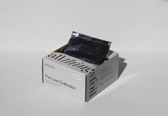 Box of 'all things foil' with black foil packets on a light gray background