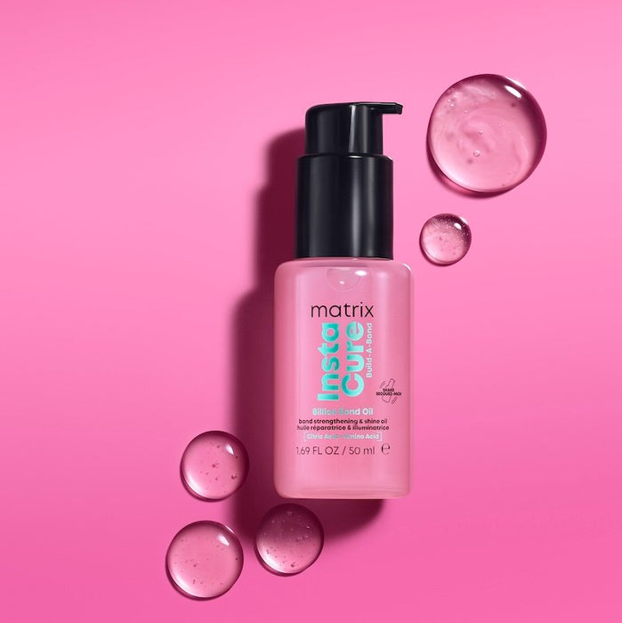 Pink bottle of Matrix InstaCure hair oil with droplets on a pink background
