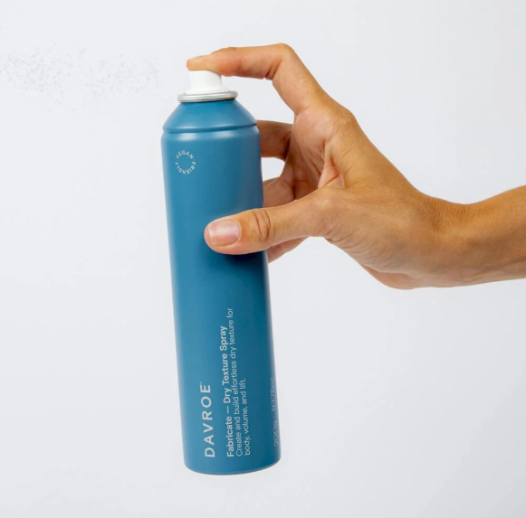 Hand holding a blue spray bottle labeled 'Davroe' against a white background