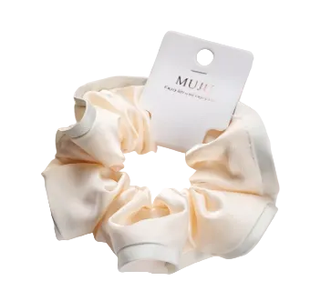 Cream-colored scrunchie with a 'MUJI' tag on a white surface