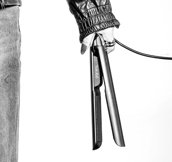 Person holding a hair straightener with 'Yokubo' branding on a white background