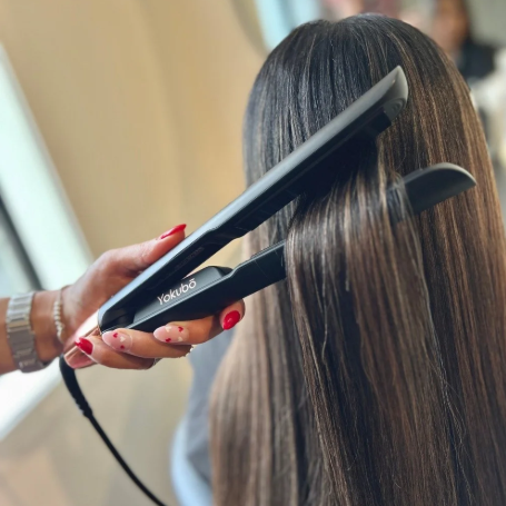 Person using a hair straightener on another person's hair